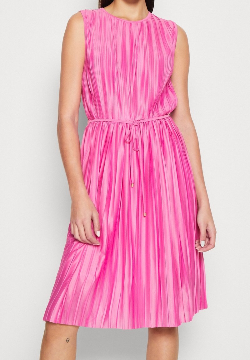 Różowa plisowana sukienka z okrągłym dekoltem, bezrękawowa, z regulowanym paskiem w talii i złotymi akcentami. Gładka faktura.