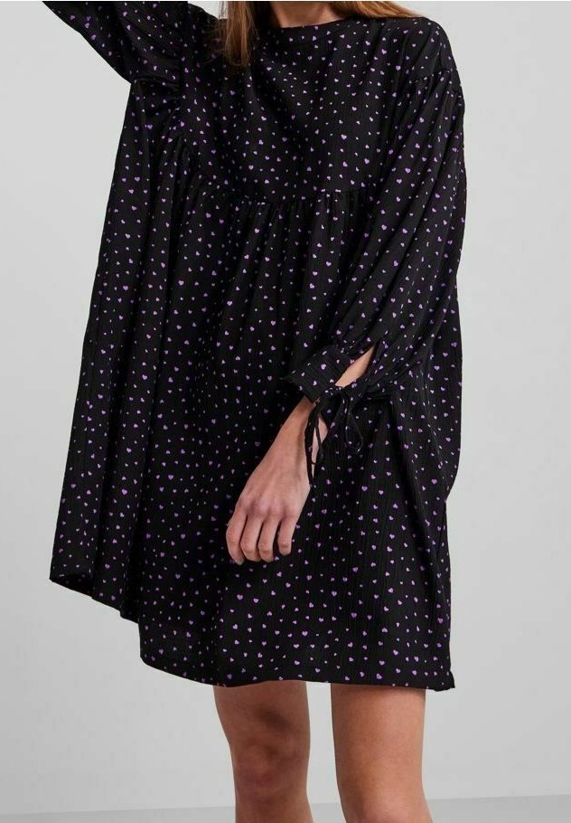 Černé volné šaty s nařaseným designem a drobnými vzory fialových srdíček, dlouhými rukávy a detailem zavazování u manžet.