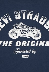 Marineblå T-skjorte med hvit grafisk tekst og en motorsykkelillustrasjon, der "Levi Strauss" og "The Original" er tydelig vist.