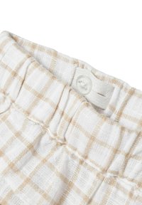 Vitt tyg med ett beige rutmönster, utrustat med en rynkad midja och en knappknäppning. Texturen verkar mjuk och lätt.