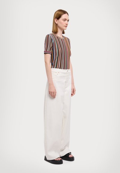 T-shirt rayé multicolore en tissu tricoté, associé à un pantalon large taille haute blanc et des sandales à plateforme noires.