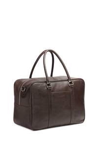 Borsa da viaggio in pelle marrone con doppie maniglie, forma rettangolare, texture liscia e logo discreto sul lato. Chiusura superiore con zip.