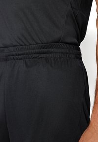 Bermudas deportivas negras con cintura elástica, textura suave y un diseño aerodinámico sin logotipos ni patrones visibles.