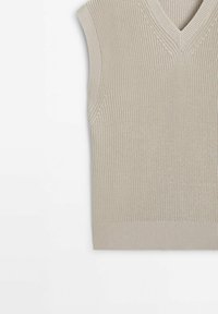 Gilet en tricot beige sans manches avec col en V, bordé de côtes à l'ourlet et aux emmanchures, posé à plat sur une surface blanche.