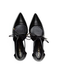 Zapatos de cuero negros con punta afilada, lados abiertos y diseño con cordones. Presentan una textura suave y acentos dorados en las ojales.