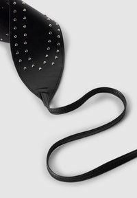 Czarny skórzany dodatek z srebrnymi ćwiekami, wydłużony w kształcie trójkąta, z cienkim paskiem i teksturowanym wykończeniem wzdłuż krawędzi.