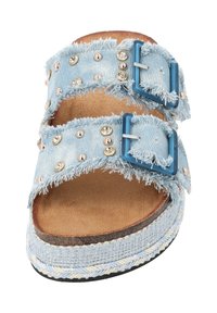 Denim slip-on sandaal met twee rafelige banden met metallic studs en blauwe gespen. Lichte blauwe kleur met een geweven, gestructureerde zool.