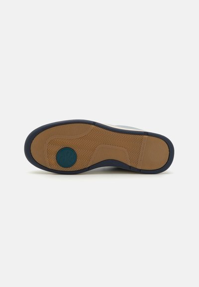 Schuhsohle aus einem Gummi-Material, mit strukturiertem Fischgrätenmuster und navyblauen Kanten. In der Mitte befindet sich ein kreisförmiges, türkisfarbenes Logo.