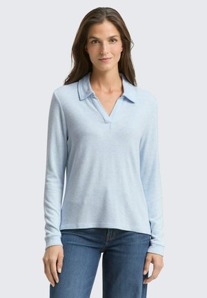 Polo shirt a maniche lunghe azzurro chiaro con colletto e texture morbida, abbinato a jeans di denim blu casual.