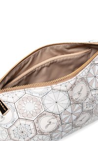 Obdélníková kosmetická taška z bílé texturované kůže, zdobená geometrickými vzory a zipem v zlatém tónu. Uvnitř podšívka z béžové tkaniny.