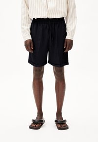 Donker marineblauwe shorts met een elastische tailleband en koord, met een relaxte pasvorm en opgerolde zomen, in combinatie met een gestreepte lange mouw shirt.