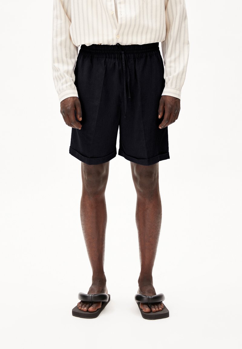 Donker marineblauwe shorts met een elastische tailleband en koord, met een relaxte pasvorm en opgerolde zomen, in combinatie met een gestreepte lange mouw shirt.