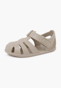 Sandalia de goma beige con diseño de punta abierta, múltiples ranuras para ventilación, correa ajustable y logotipo en relieve en el lateral.