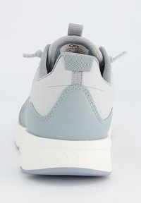 Chaussure de sport grise avec une tige en tissu texturé et des accents en cuir lisse. Présente une semelle intermédiaire blanche et une bande de traction au talon.