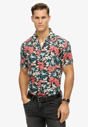 Schwarzes Kurzarmhemd mit lebhaftem Blumenmuster in Rot, Türkis und Creme; mit Kragen, Knopfverschluss vorne. Getragen mit dunklen Jeans.