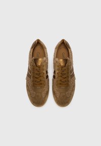 Brown sneakers with a textured upper, featuring suede and fluffy material. Laces are brown, with a metallic gold accent on the tongue.