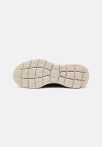 Shoe outsole with a textured cream rubber surface, featuring a grid pattern for traction and curved edge for flexibility.