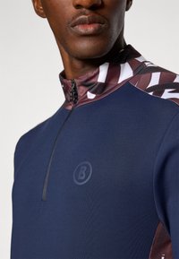 Navy cycling jersey with zip collar, featuring patterned burgundy and white accents on shoulders. Includes a subtle logo on the chest.