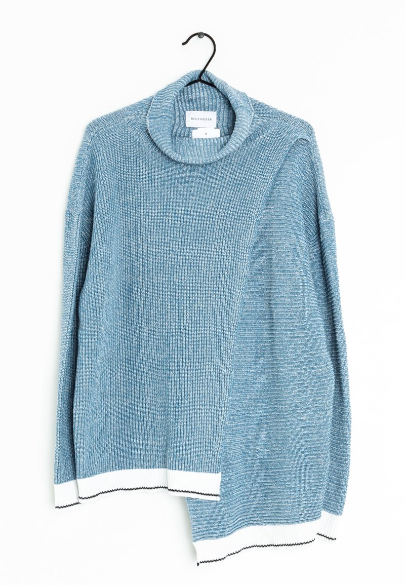 Pull en tricot bleu avec col haut replié, texture côtelée, et poignets blancs avec coutures noires, suspendu à un cintre noir sur fond blanc.