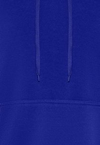 Fleece mikina v živé královské modři. Obsahuje přední kapsu, šňůrky a hladkou texturu s jednobarevným designem.