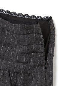 Zwart en grijs gestructureerde jurk met een houndstooth patroon, voorzien van een textuurstof, kantafwerking en een ritssluiting aan de zijkant.