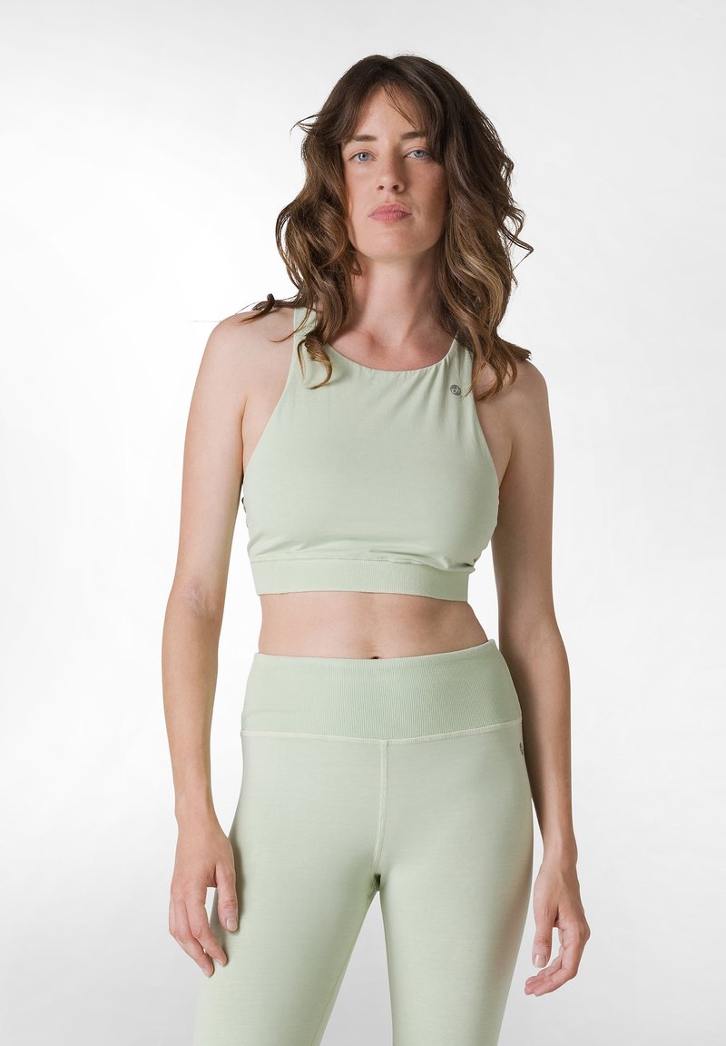 Ljust grön croppad topp med rund halsringning och knapppdetail, tillverkad av mjukt, elastiskt tyg. Matchas med högmidjade leggings i samma färg.