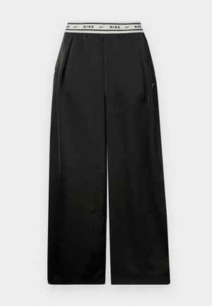 Pantalon à jambes larges noir en tissu lisse, avec une ceinture élastique blanche portant le logo "NIKE". Des plis ajoutent de la dimension et de la texture.
