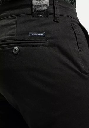 Czarne spodnie wykonane z bawełny, z zapięciem na guzik, tylną kieszenią z etykietą "CROSS JEANS" oraz teksturowanym materiałem.