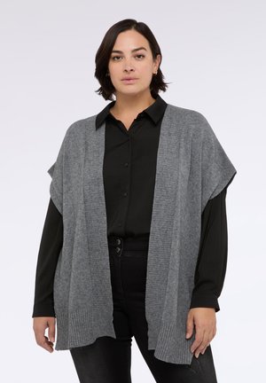 Cardigan grigio lavorato a maglia con orlo a coste, apertura frontale e maniche corte. Abbinato a una camicia nera con colletto e jeans neri.