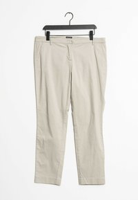 Pantalones de algodón beige colgados en una percha negra, con un diseño de pierna recta, dos bolsillos frontales y sin patrones o herrajes visibles.