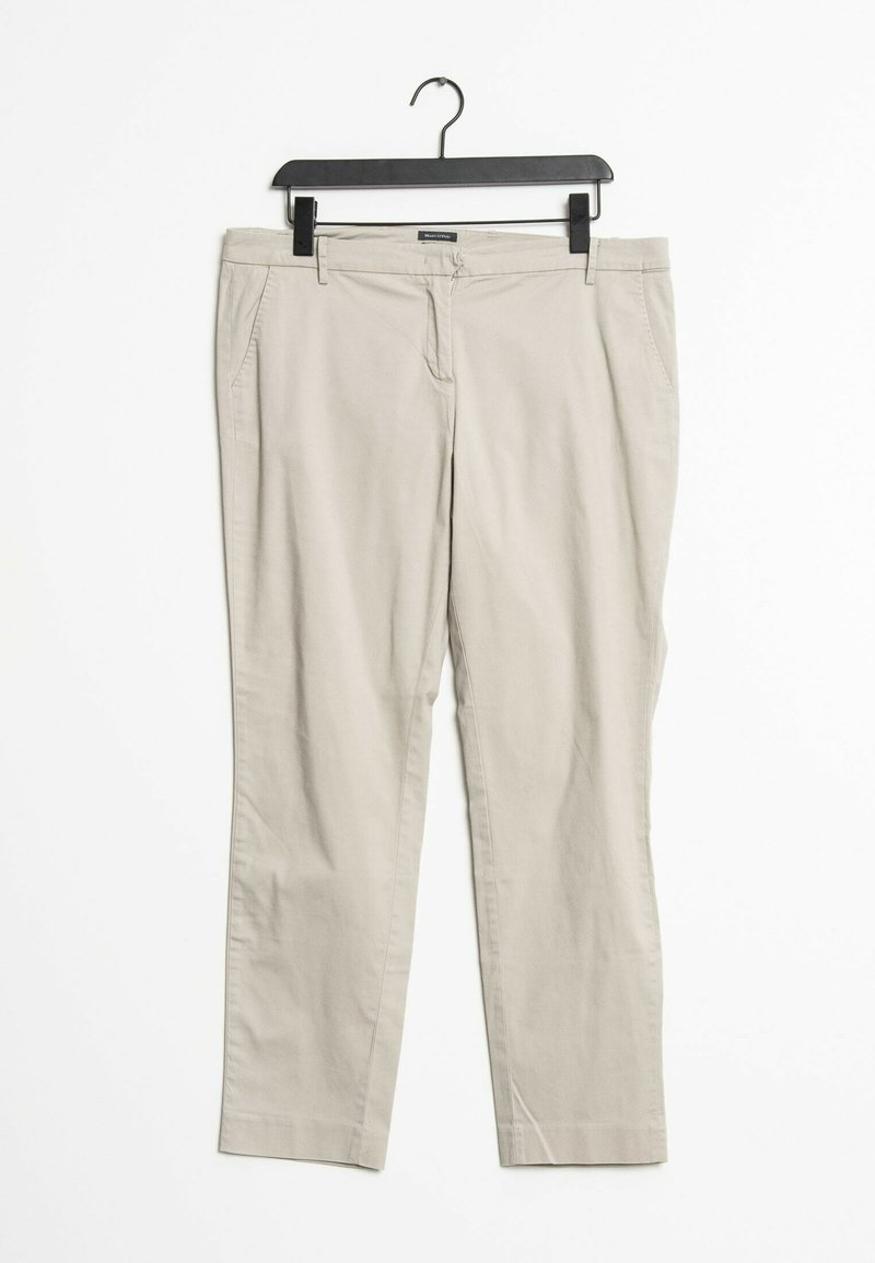 Pantalones de algodón beige colgados en una percha negra, con un diseño de pierna recta, dos bolsillos frontales y sin patrones o herrajes visibles.