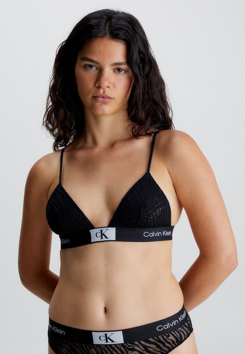 Bralette nera a triangolo con tessuto texturizzato, spalline sottili e un elastico con logo. Abbinato a un perizoma nera con logo coordinato.