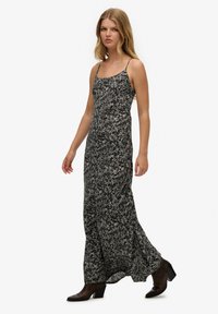 Czarna i biała maxi sukienka w kwiatowy wzór z cienkimi ramiączkami. Zwiewny materiał układa się do kostek, w połączeniu z ciemnymi, wysokimi botkami.
