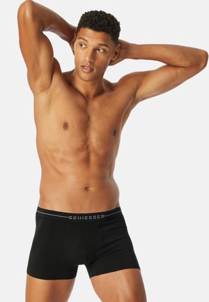 Schwarze Boxershorts aus glattem Stoff mit einem elastischen Bund, der den Markennamen "Schiesser" in silberner Schrift trägt.