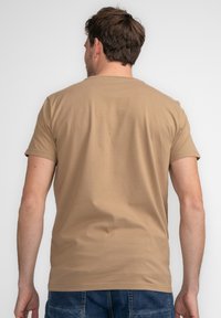 Brun, kortærmet T-shirt med rund halsudskæring, lavet af bomuld, har en glat tekstur og ensfarvet design. Synlige sømme langs kanten.