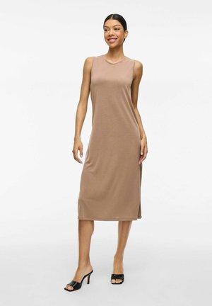 Vestido sin mangas color tostado con un corte relajado, a la altura de la rodilla, con aberturas laterales, textura suave y escote redondo. Se lleva con tacones negros de punta abierta.