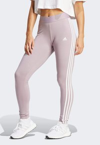 Svetlo purpurne tajice z gladko teksturo, ki imajo tri bele stranske črte in logotip Adidas na levi boki.