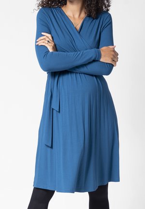 Blaues Wickelkleid aus weichem Stoff, mit langen Ärmeln, einem geschichteten Design, einer Taillenschleife und einem knielangen Saum.