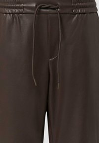 Bruine faux leren joggers hebben een elastische tailleband met trekkoord en zijzakken. Het oppervlak heeft een gladde, matte afwerking.