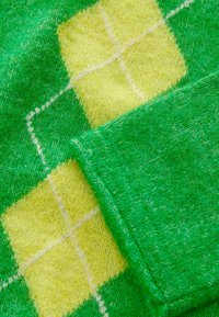 Groen en geel gemusterde stof met een ruitpatroon, met een zachte textuur en contrasterende kleuren in een gezellige breimateriaal.