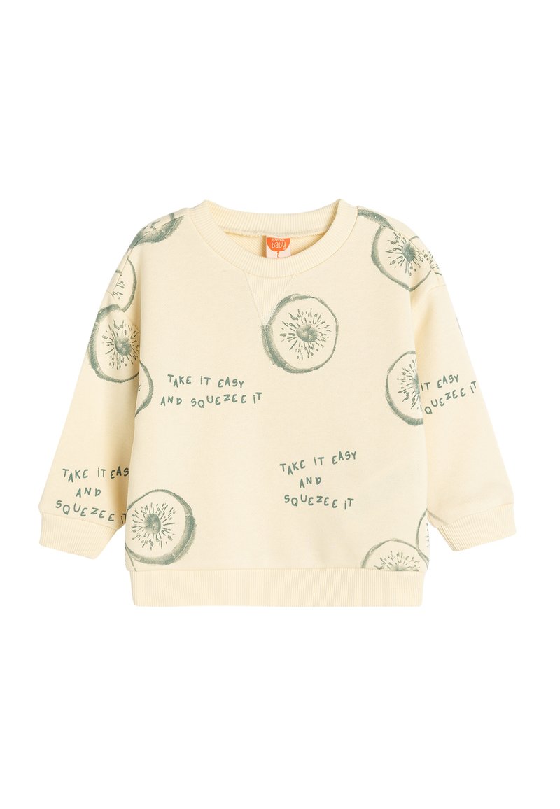 Sweatshirt color crema con illustrazioni di kiwi verdi e testo che dice: "Prendila con calma e spremila." Polsini e orlo a costine.