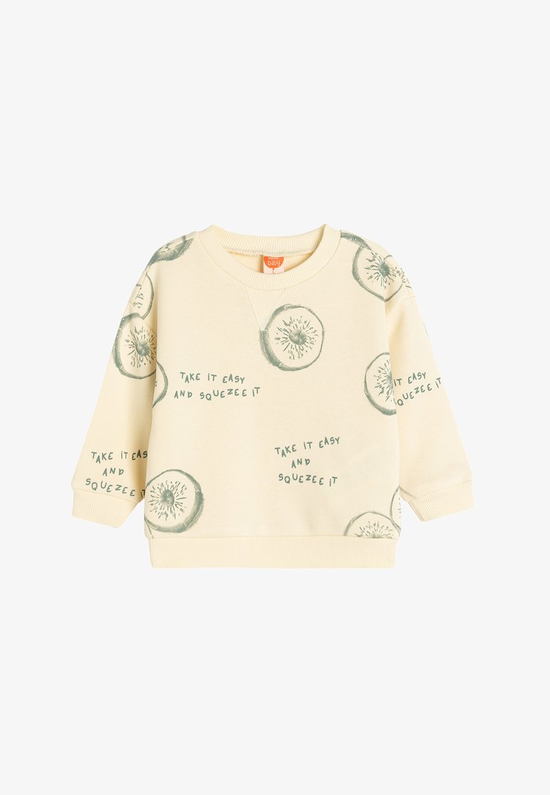 Sweatshirt color crema con illustrazioni di kiwi verdi e testo che dice: "Prendila con calma e spremila." Polsini e orlo a costine.