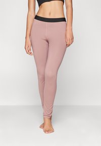 Mauve tajice s crnim elastičnim pojasom, s glatkom teksturom i prilagođenim dizajnom, koji se proteže do gležnjeva.