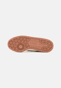 Semelle de chaussure avec motifs de sculpture circulaires et linéaires, avec logo et marque adidas sur une semelle extérieure en caoutchouc marron clair.