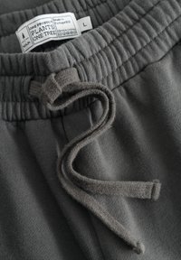 Gray cotton blend joggers featuring a soft texture, elastic waistband, and flat drawstring. Includes a care label with brand details.
