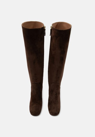 Paire de bottes hautes en suède marron foncé avec fermetures éclair latérales, vues de face sur fond blanc.