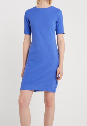 Femme portant une robe en maille côtelée bleu vif, ajustée, arrivant au genou, avec des manches courtes et un col rond.