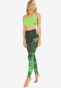 Grünes Sport-BH- und Leggings-Set mit geometrischem Muster in verschiedenen Grüntönen, aus dehnbarem Material mit glatter Textur.