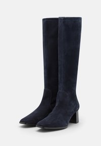 Knee-high, granatowe zamszowe kozaki z ostrym noskiem i blokowym obcasem. Gładka faktura, minimalne szwy i dopasowana sylwetka.