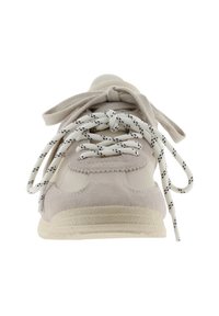 Vista frontal de una zapatilla beige con suela gruesa y doble cordón, uno sólido beige y otro blanco con detalles en negro, atados en lazos.